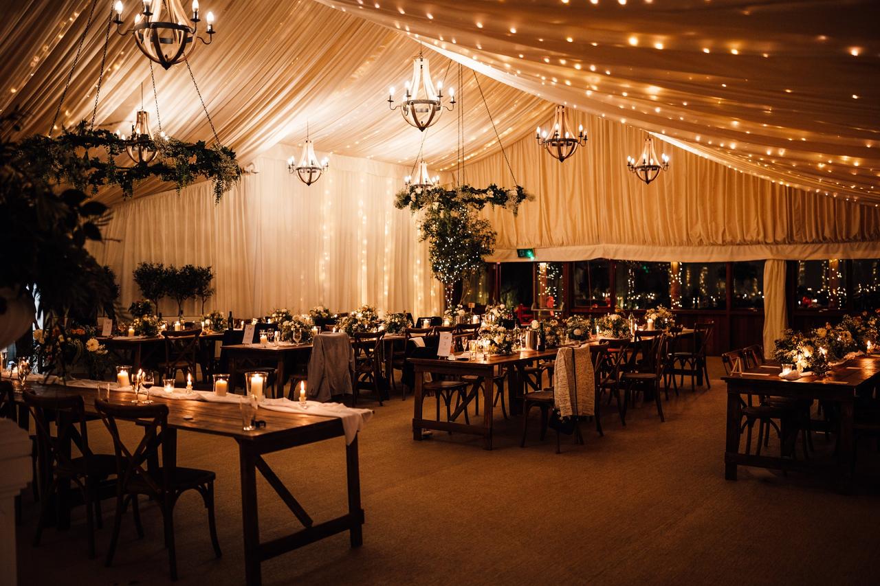 Inside marquee wedding breakfast at Crockwell Farm, Northamptonshire with fairy lights.
