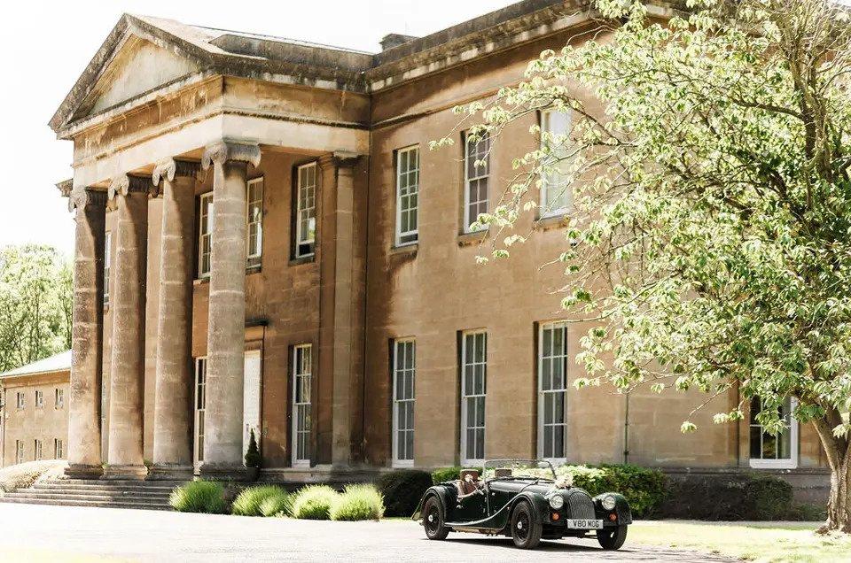 Grand sandstone building with a vintage car parked outside