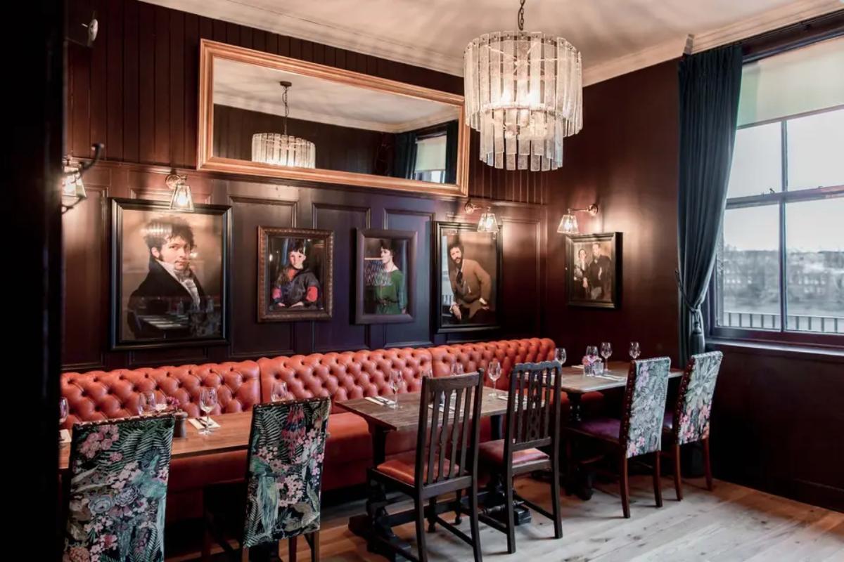  the interior of the old ship london wedding venue with red leather benches and embroidered chairs