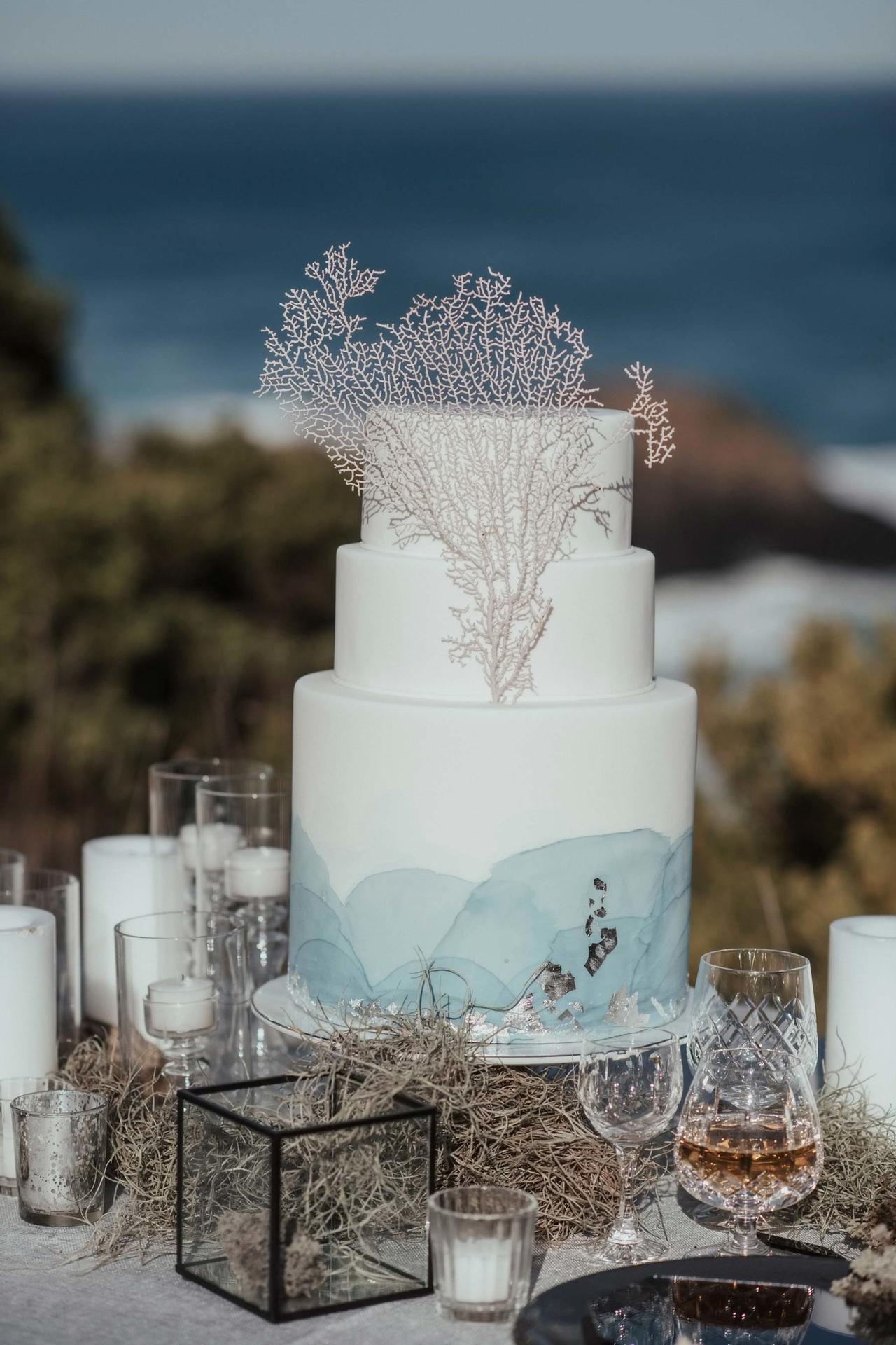 Three tiered white and blue fondant rustic wedding cake with coral