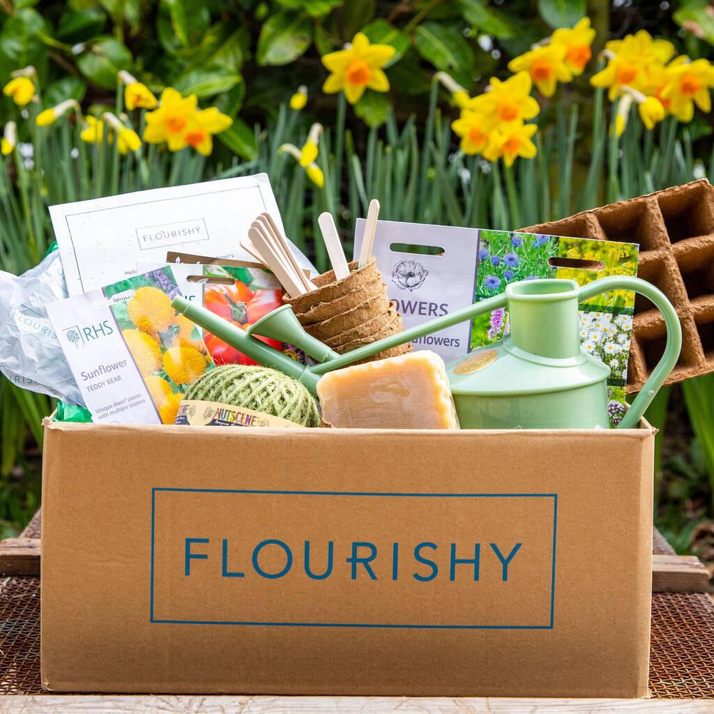 a cardboard box full of gardening tools in front of a row of daffodils