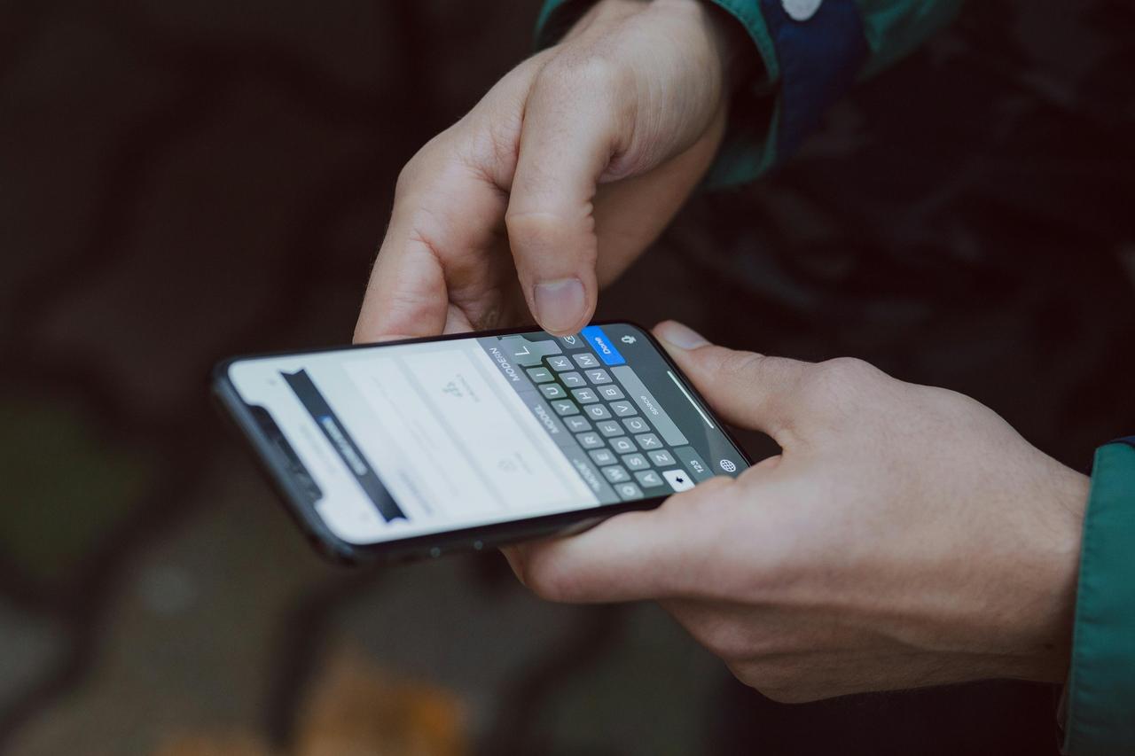 A close up of a man holding an iphone reading a good morning message.