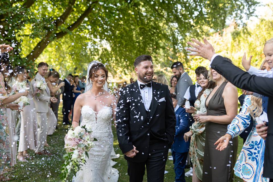 dream wedding competition winners kayleigh and ryan walking through a procession of their guests as they throw confetti over them
