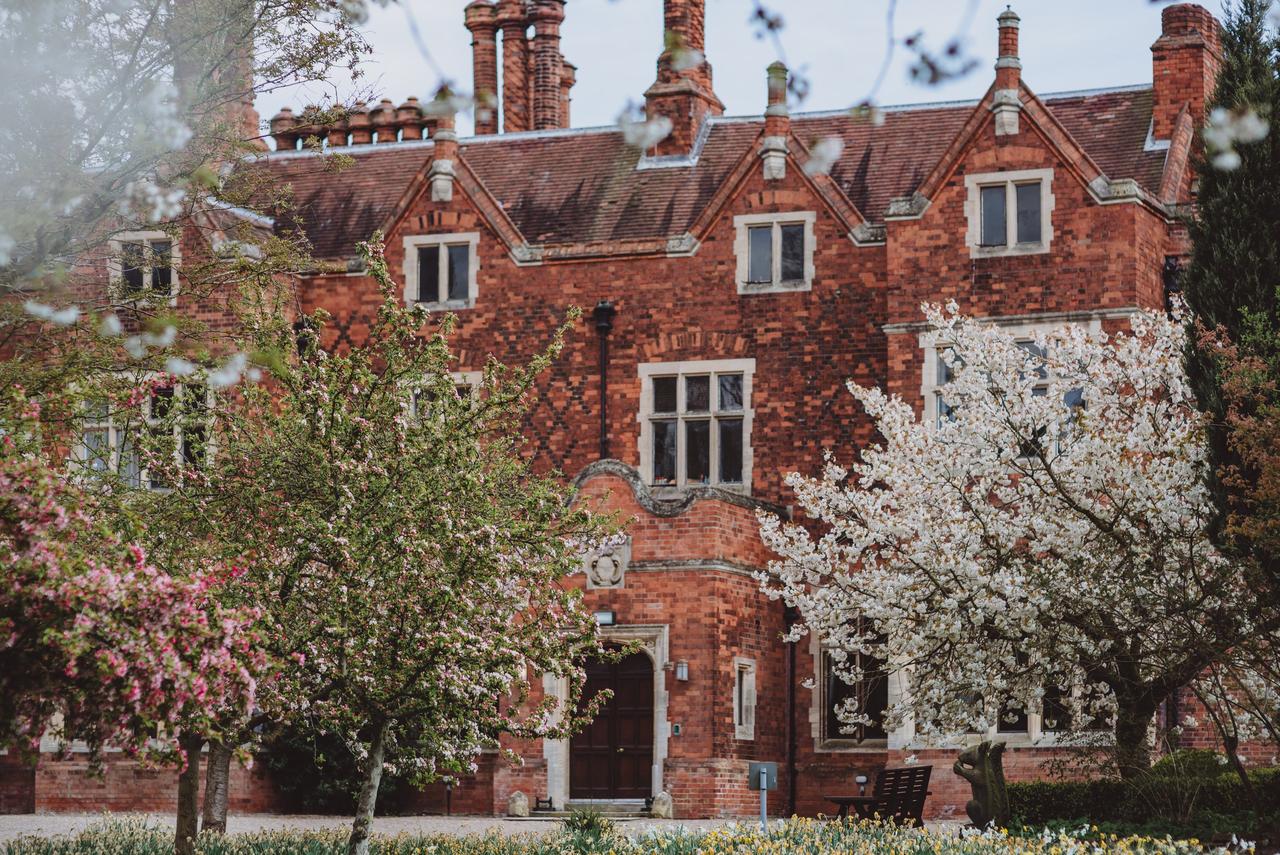 Historic priory wedding venue with blossom trees in the foreground