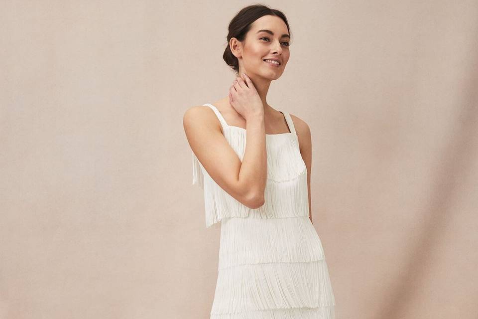 Model wearing a white fringe wedding dress