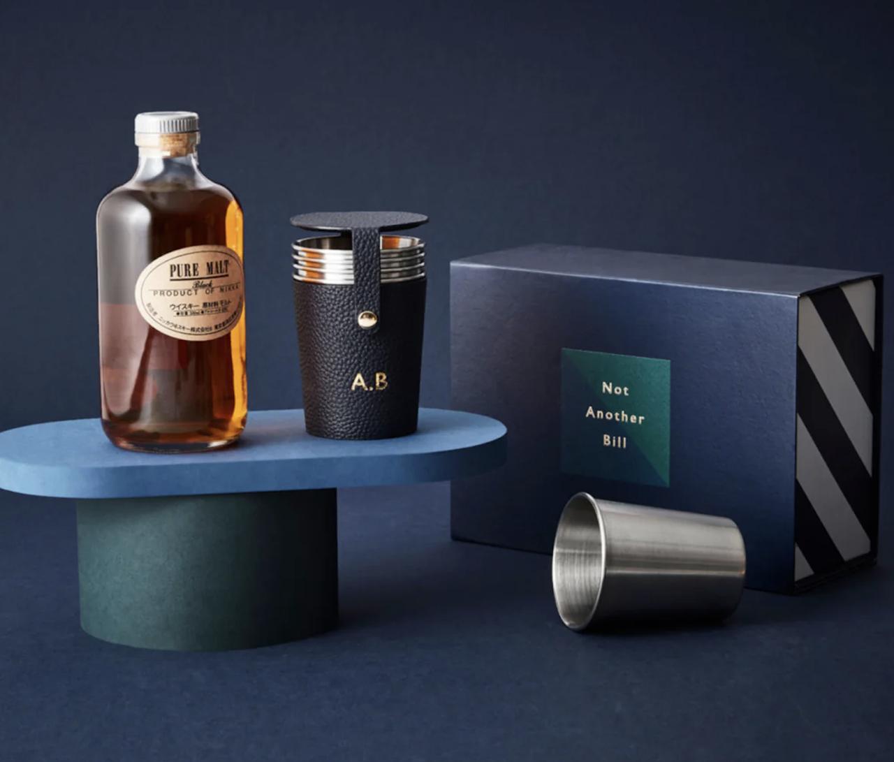 embossed leather travel shot set on display next to a bottle of alcohol and a gift box