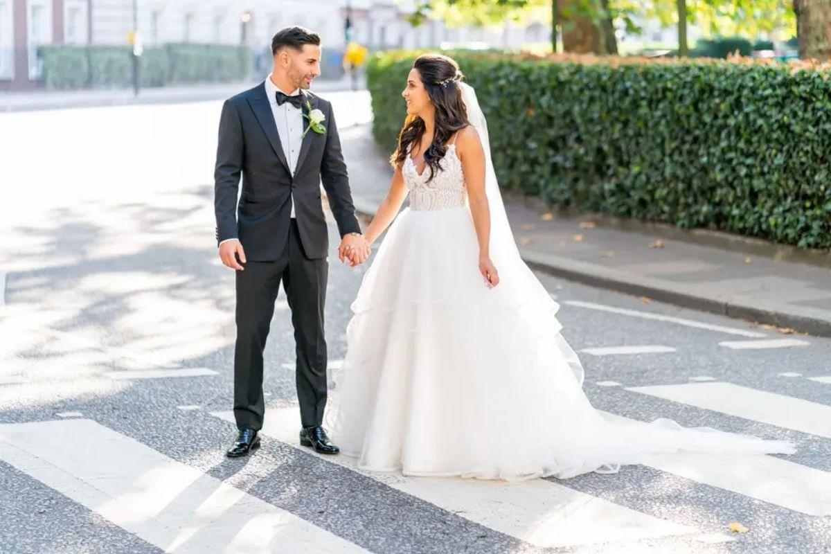 a bride and groom hold hands and pose in the road after their chic city wedding
