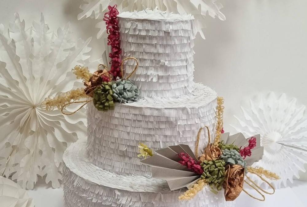 https://cdn0.hitched.co.uk/article/7516/original/1280/png/136157-33-a-pinata-in-the-shape-of-a-three-tier-white-wedding-cake-with-floral-decorations-and-white-hanging-garlands-in-the-background.jpeg