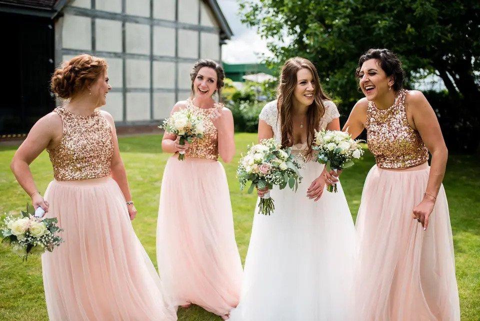 Candid shot of a bride with bouquet and three bridesmaids on a lawn outside the wedding venue