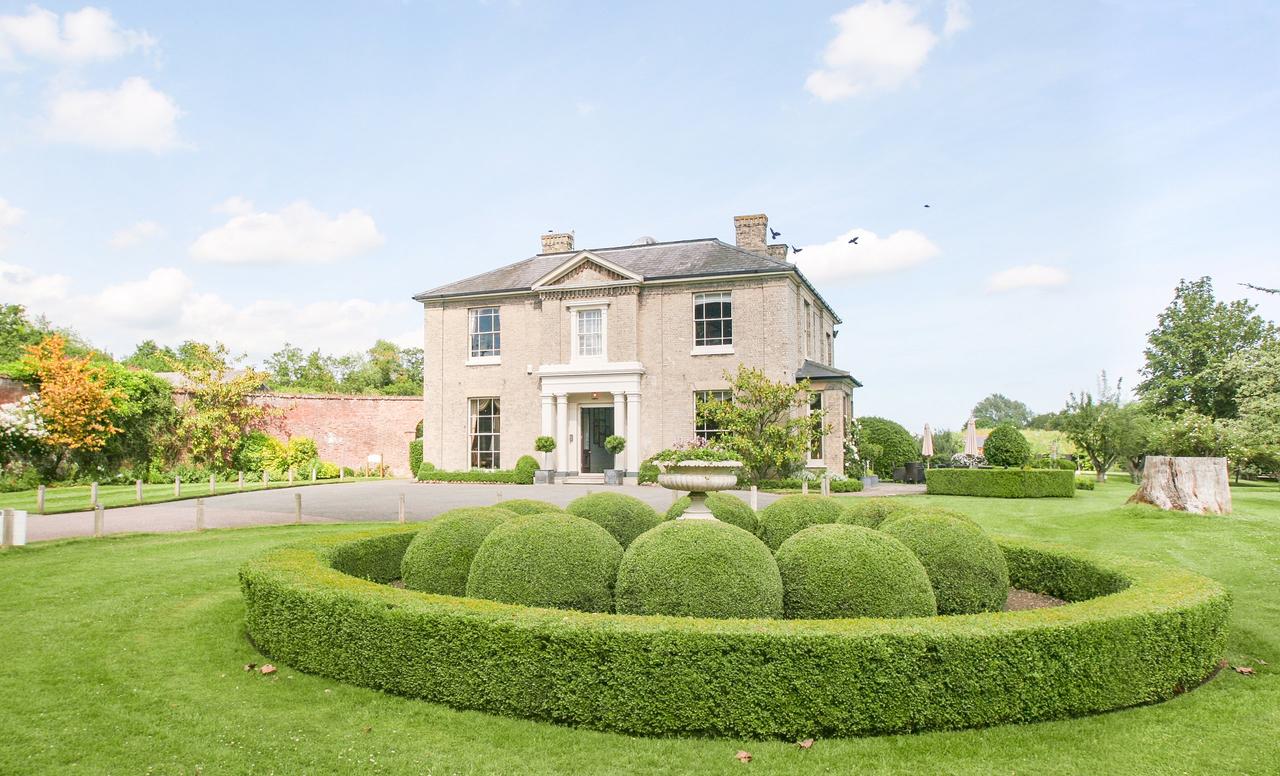 A georgian stately manor house with a manicured display of topiary in the foreground