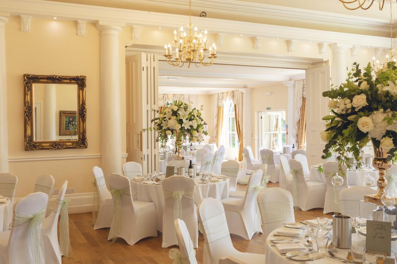 Interior of a Georgian-style dining room set up with round tables for a wedding breakfast.
