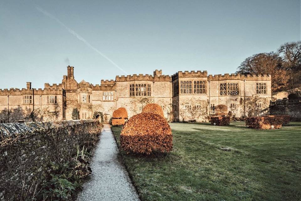 Exterior view of Haddon Hall, which features stone walls, green gardens, and a stone pathway