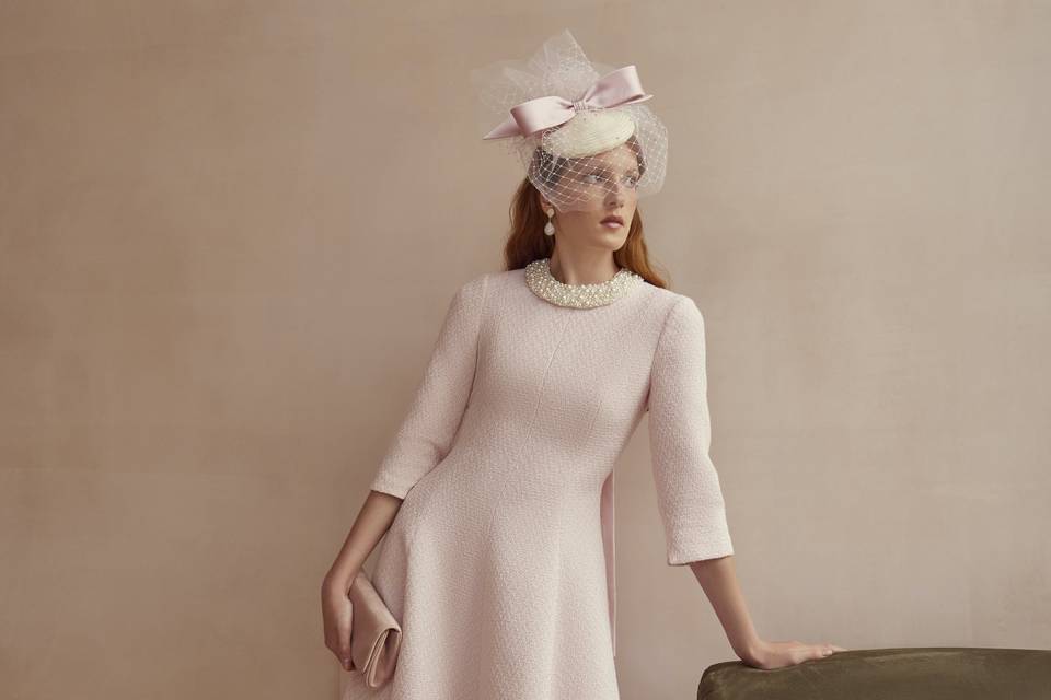 A mother of the groom wearing a pale pink three-quarter-length sleeve dress with jewelled embellishment around the neckline.