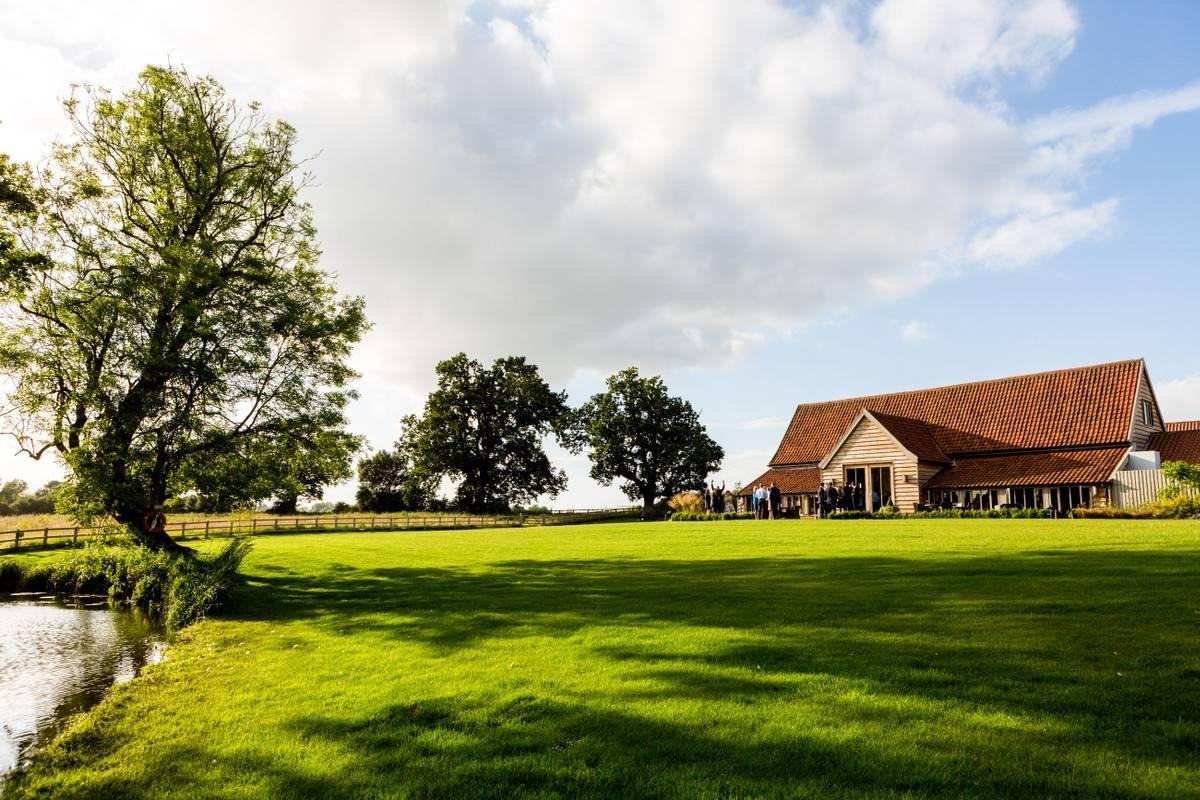A large lawn and lake situated in front of a purpose built Suffolk wedding venue 