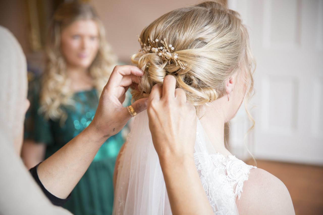 blonde low bun with pearls being arranged on a bride