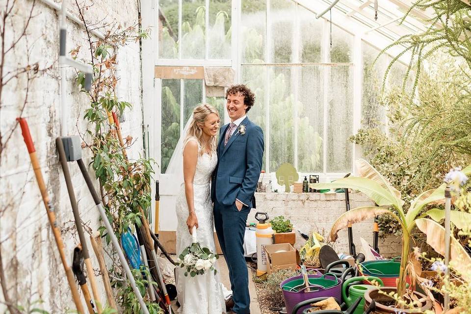 Bride and groom laughing in a greenhouse