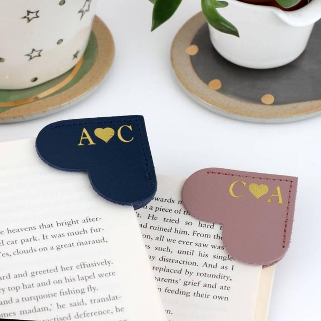 Two open books featuring a monogrammed heart-shaped corner bookmark on each page.