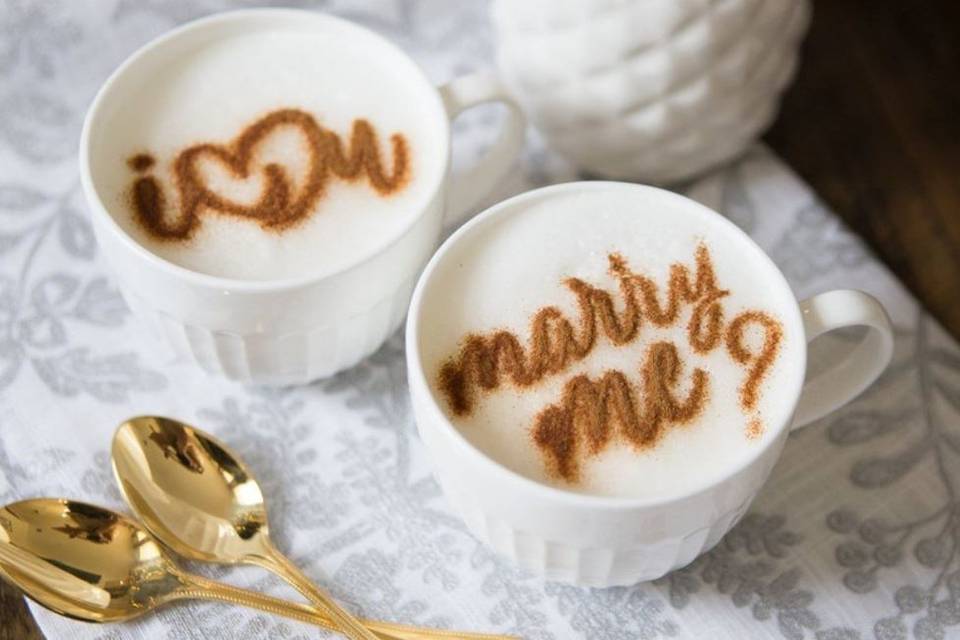 romantic at home proposal idea showcasing two white mugs with the words I love you and marry me on top of two coffees