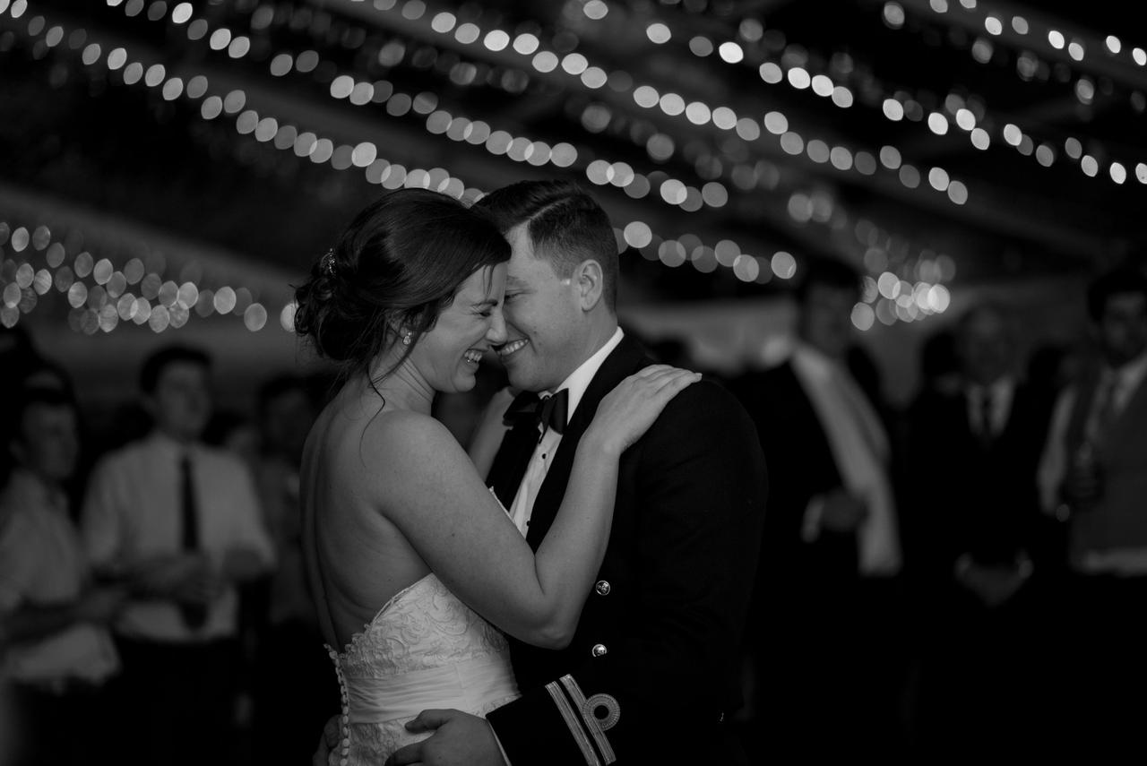 black and white editorial style photo of a bride and groom laughing during their first dance