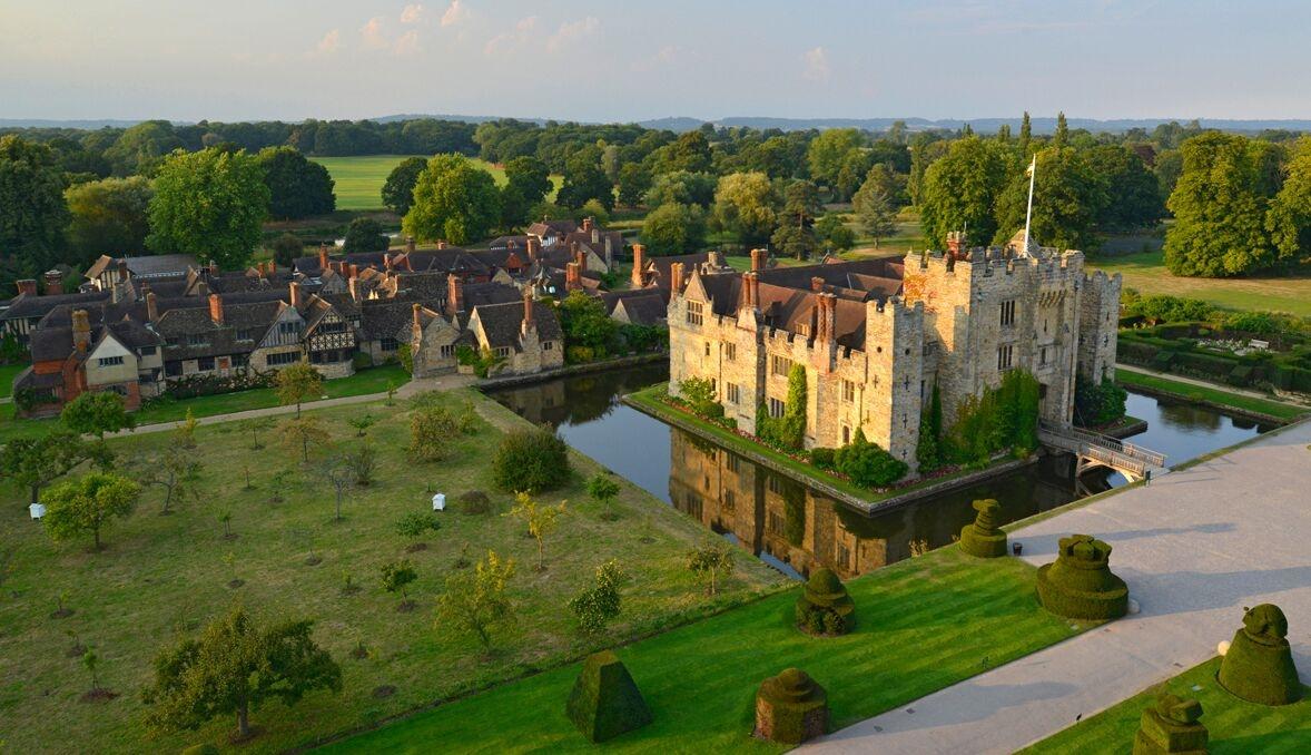 Large historic castle situated within a moat in a rural countryside village