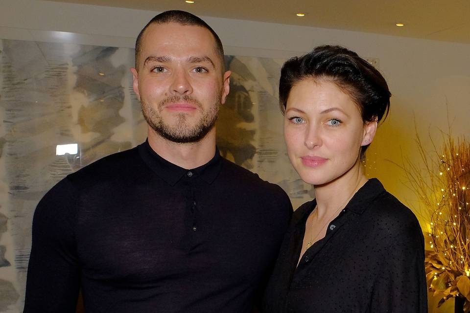 Emma and Matt Willis both wearing black outfits posing in front of a light yellow background
