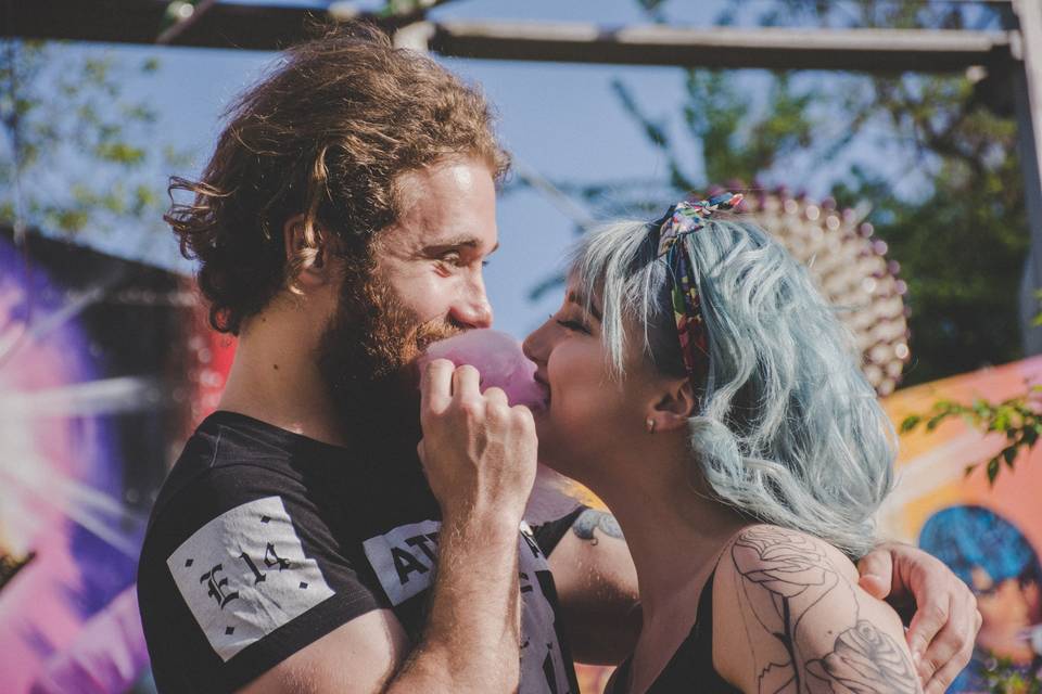 Newly engaged couple at a funfair sharing candy floss and laughing at each other