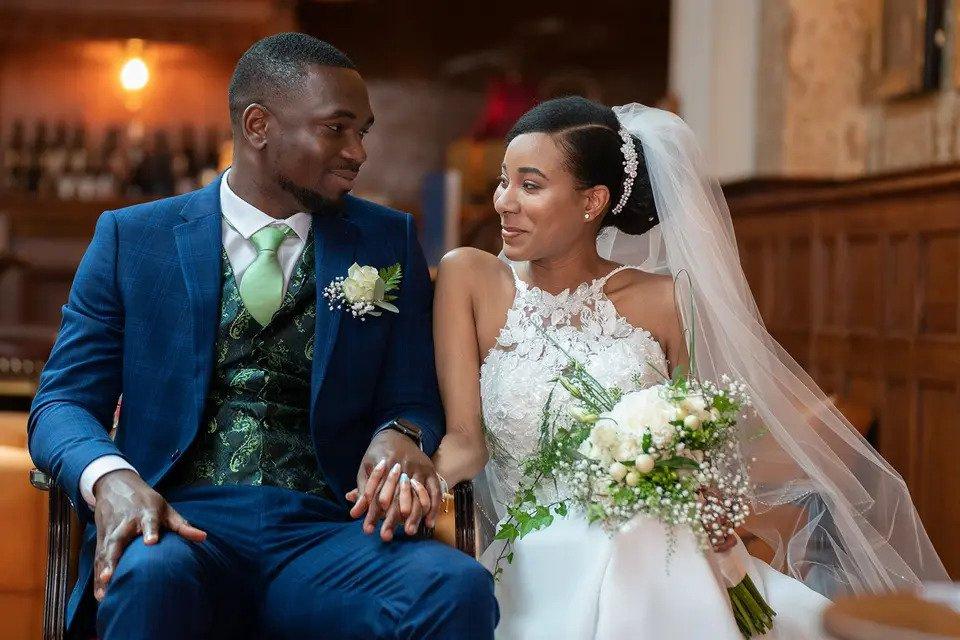Seated bride and groom gaze at each other in a church