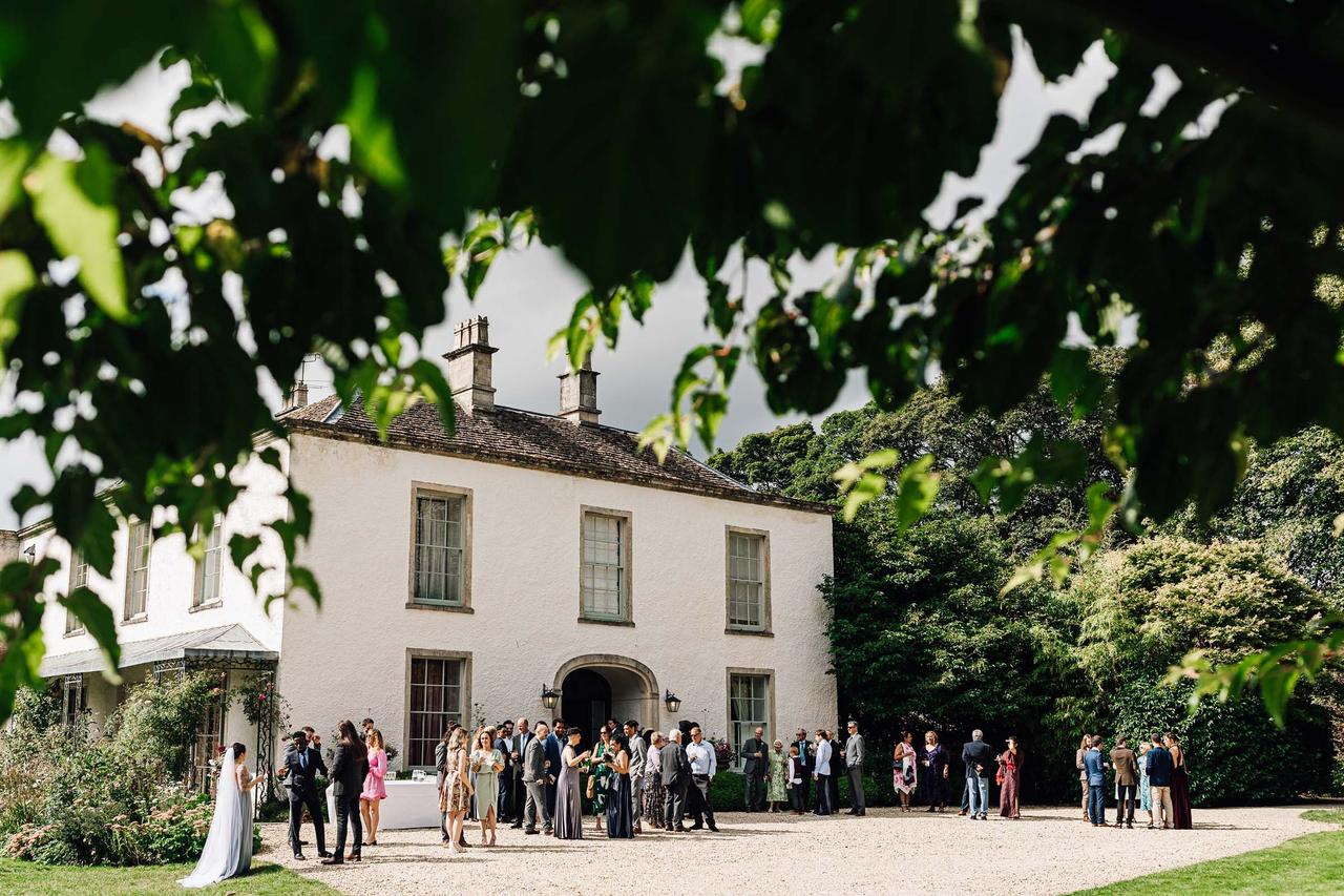 Wedding guests congregating outside of a georgian wedding venue with a white exterior