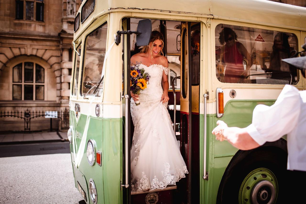A bride steps out of a vintage minivan