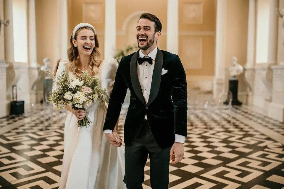 Bride and groom laughing hand in hand as they leave their wedding ceremony