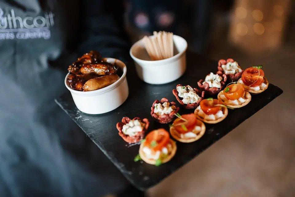 Waiter with company apron holding a tray of canapes