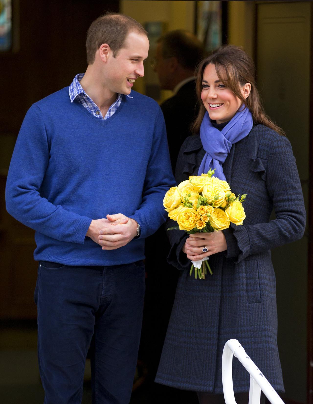 Prince William and Kate Middleton stand together holding yellow flowers