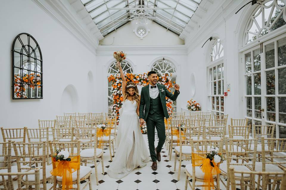 Couple punching the air at a wedding ceremony in an orangery at one of the UK's best wedding venues