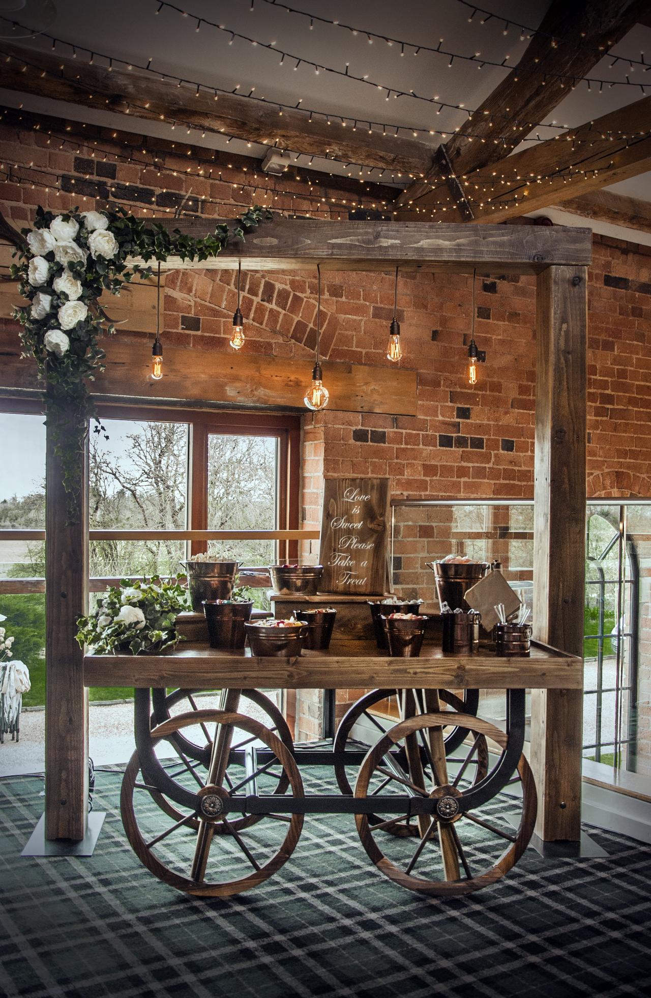 A simple wooden arch with Edison bulbs dangling from centre to light up sweet cart