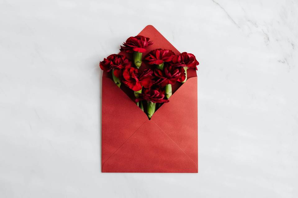 A red envelope filled with red carnations.