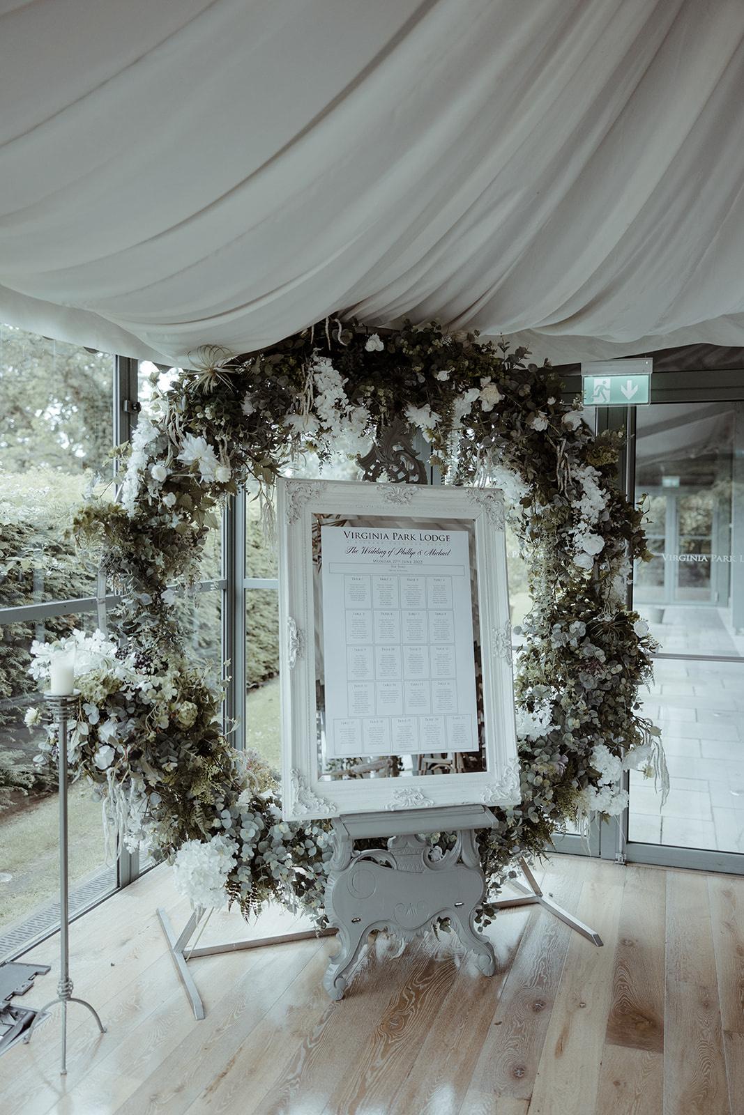 The table plan set in a white frame surrounded by a circle of florals