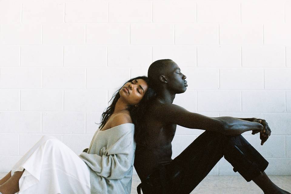 Couple sitting back to back looking sad and disconnected as one wants marriage and the other doesnt