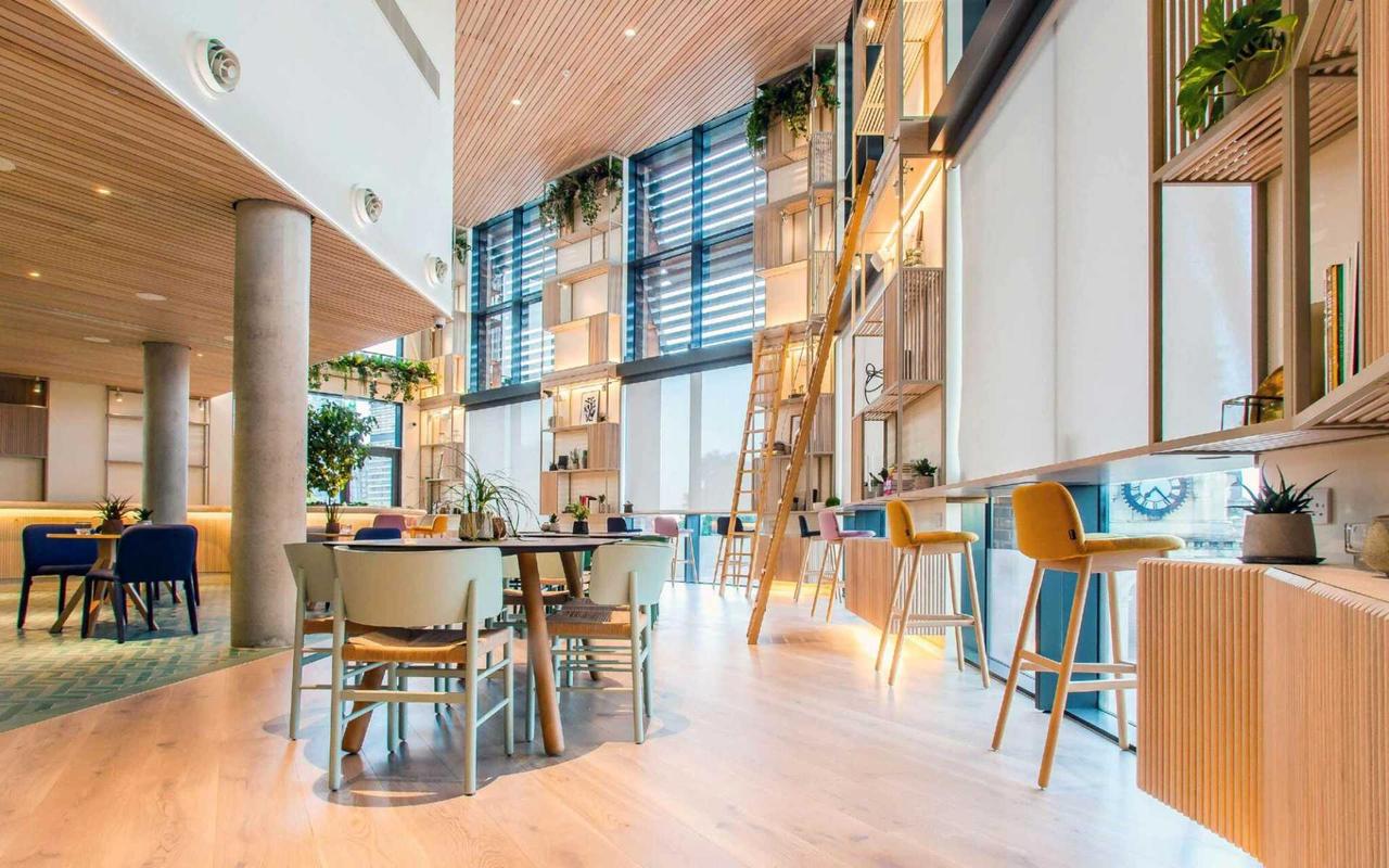 A bright modern wedding venue with double-height ceilings, colorful furnishings, floor-to-ceiling shelves, and large windows 
