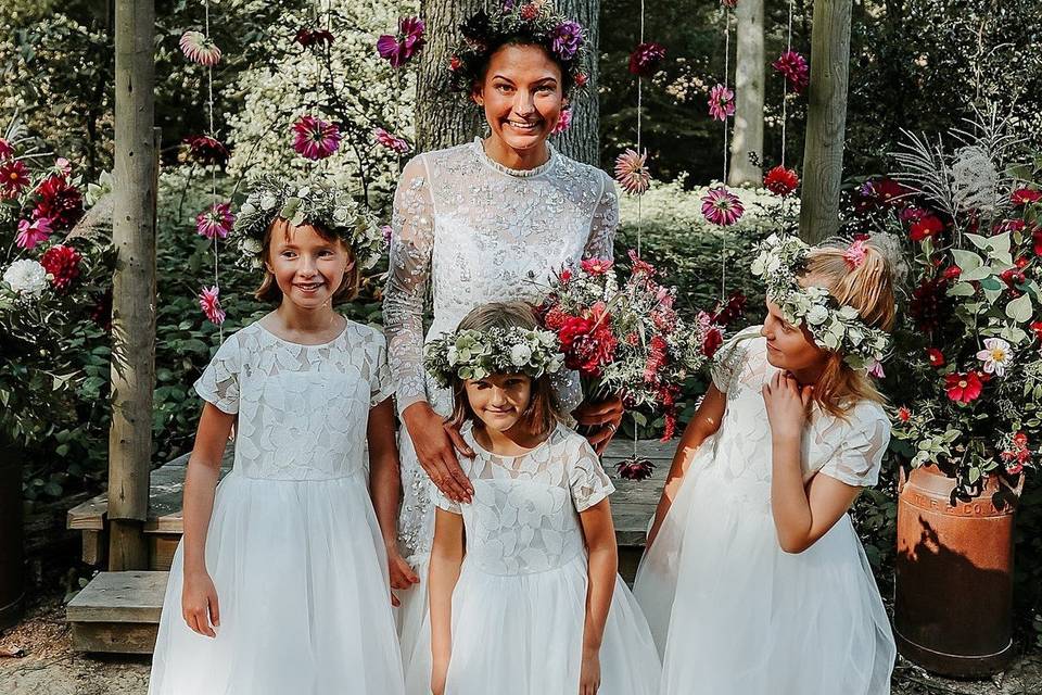 Bride surrounded by three adorable flower girls wearing white dresses and flower crowns