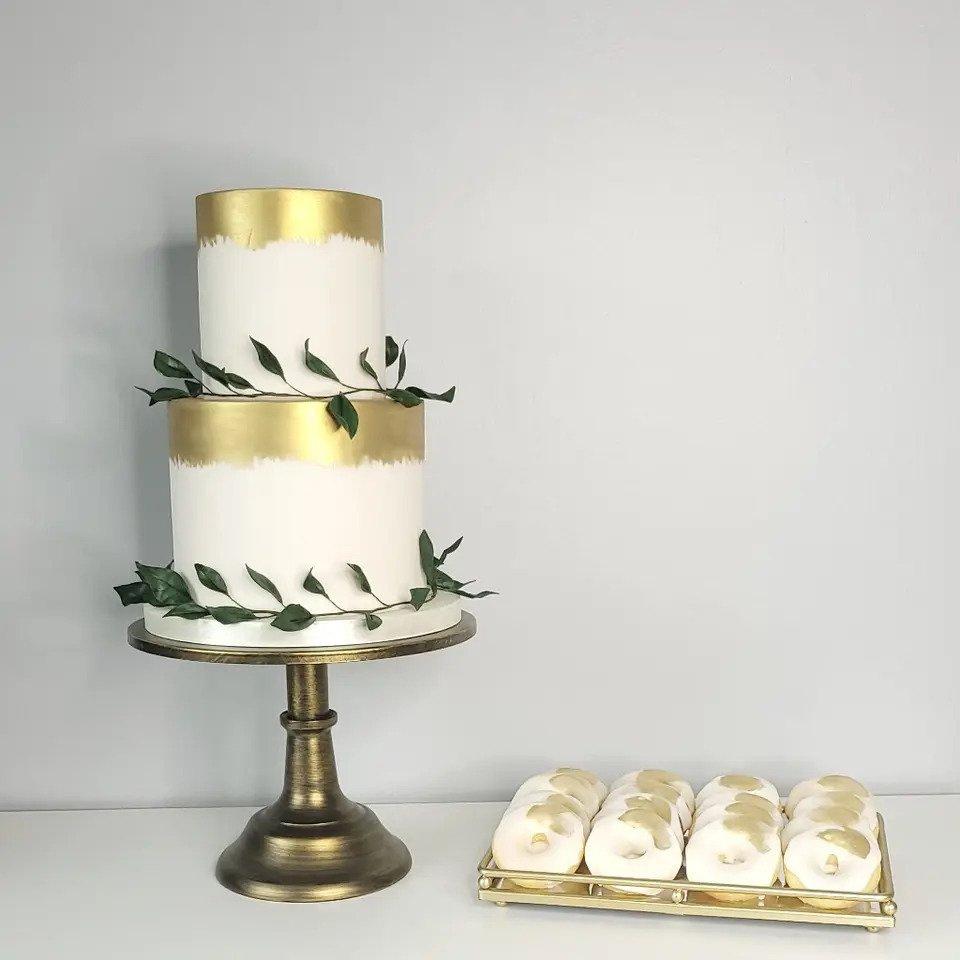 gold white and green wedding cake with fresh greenery