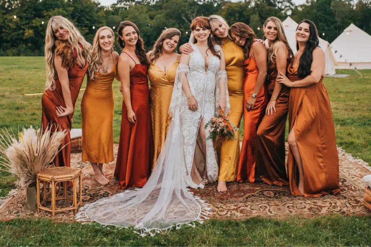 eight bridesmaids in autumnal satin dresses with a bohemian bride at her wedding
