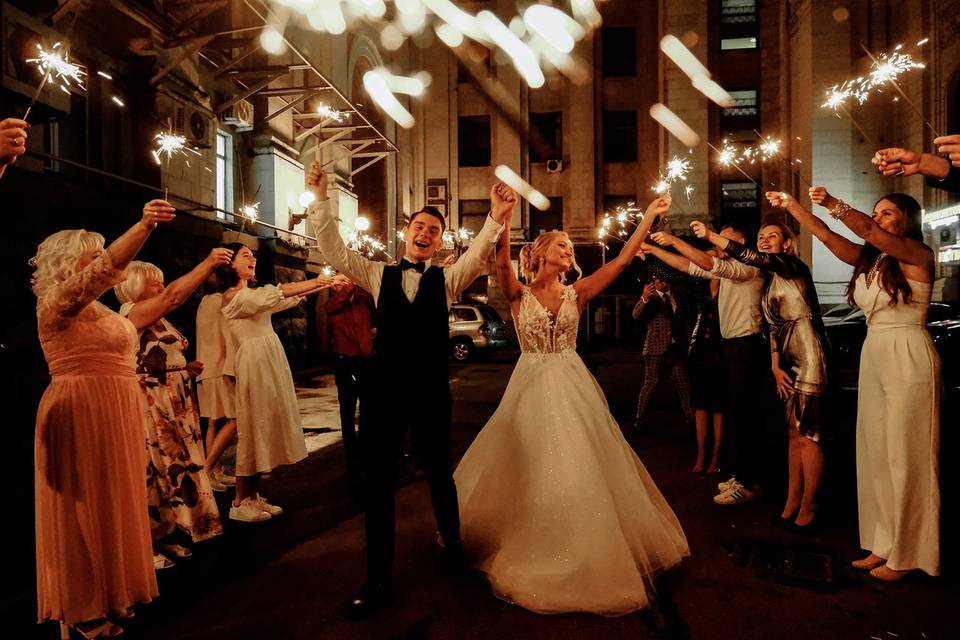 Couple dancing to the first dance song at their wedding as their guests hold up sparklers