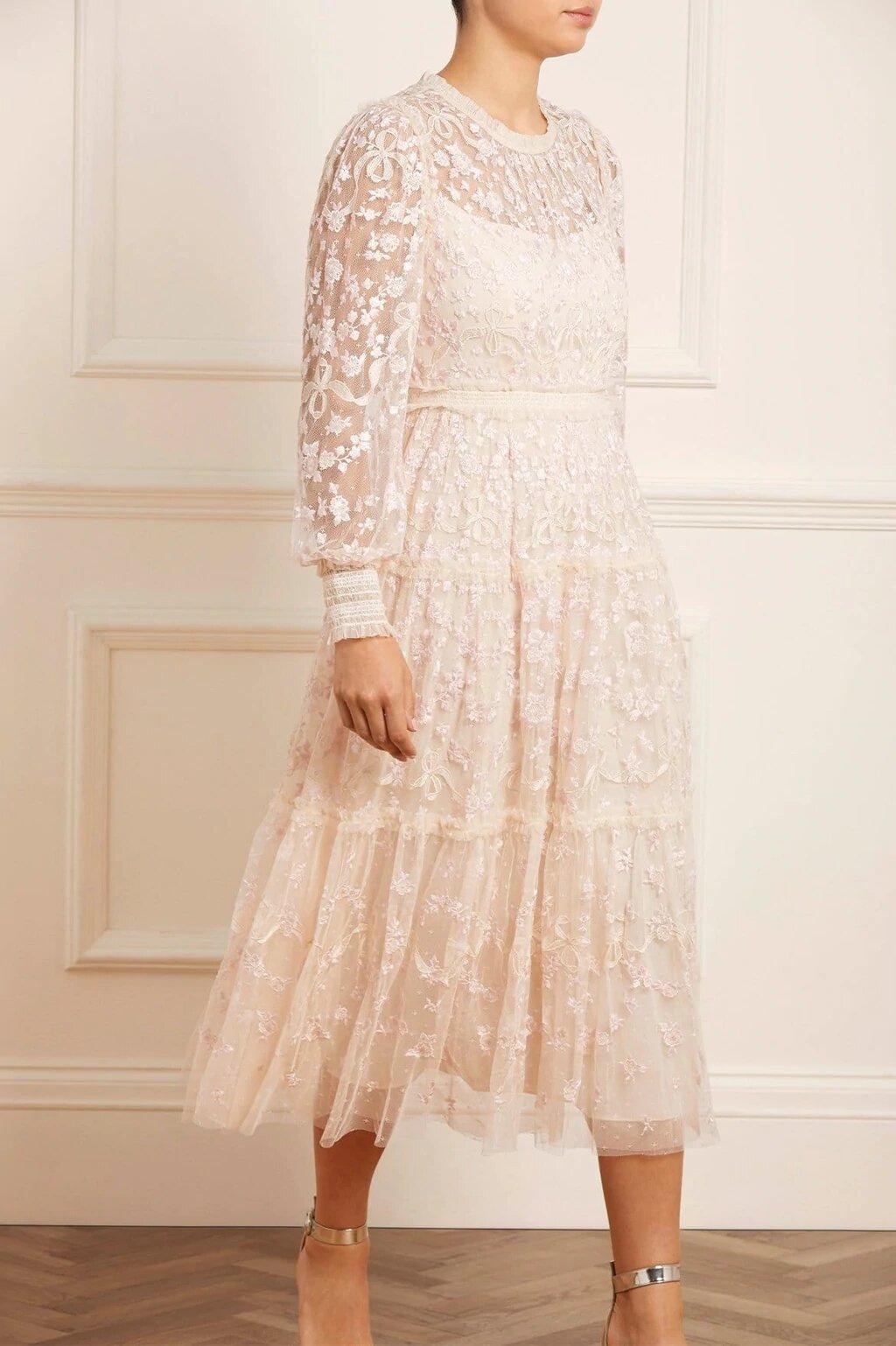 Model wearing an embellished long sleeved tea length wedding dress