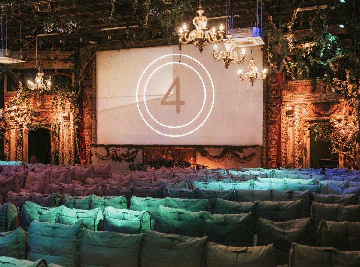 Opulent cinema with chandeliers and green ivy with a countdown on the projector screen