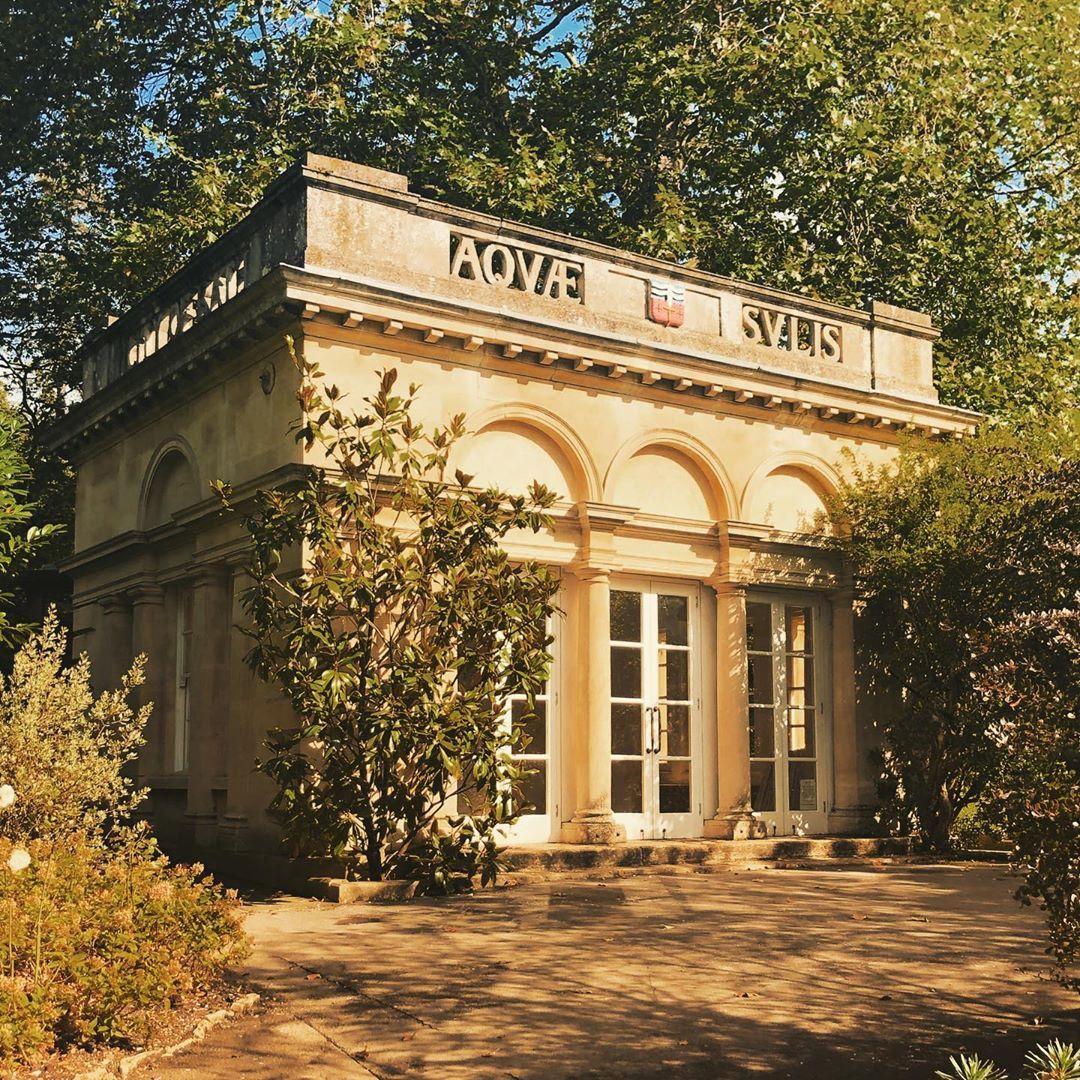 Exterior of the Temple of Minerva, a honey-coloured square stone building with doors that have glass panes