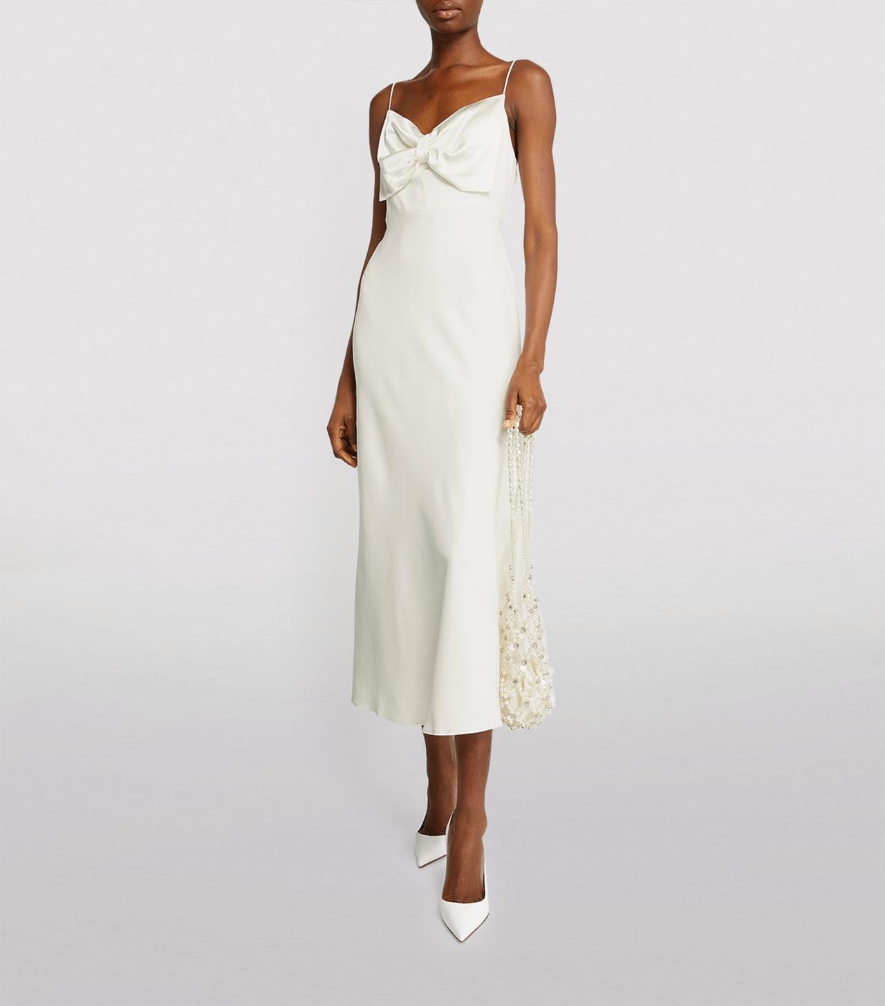 Black woman wearing a white slip wedding dress with a bow front and white stilettos 