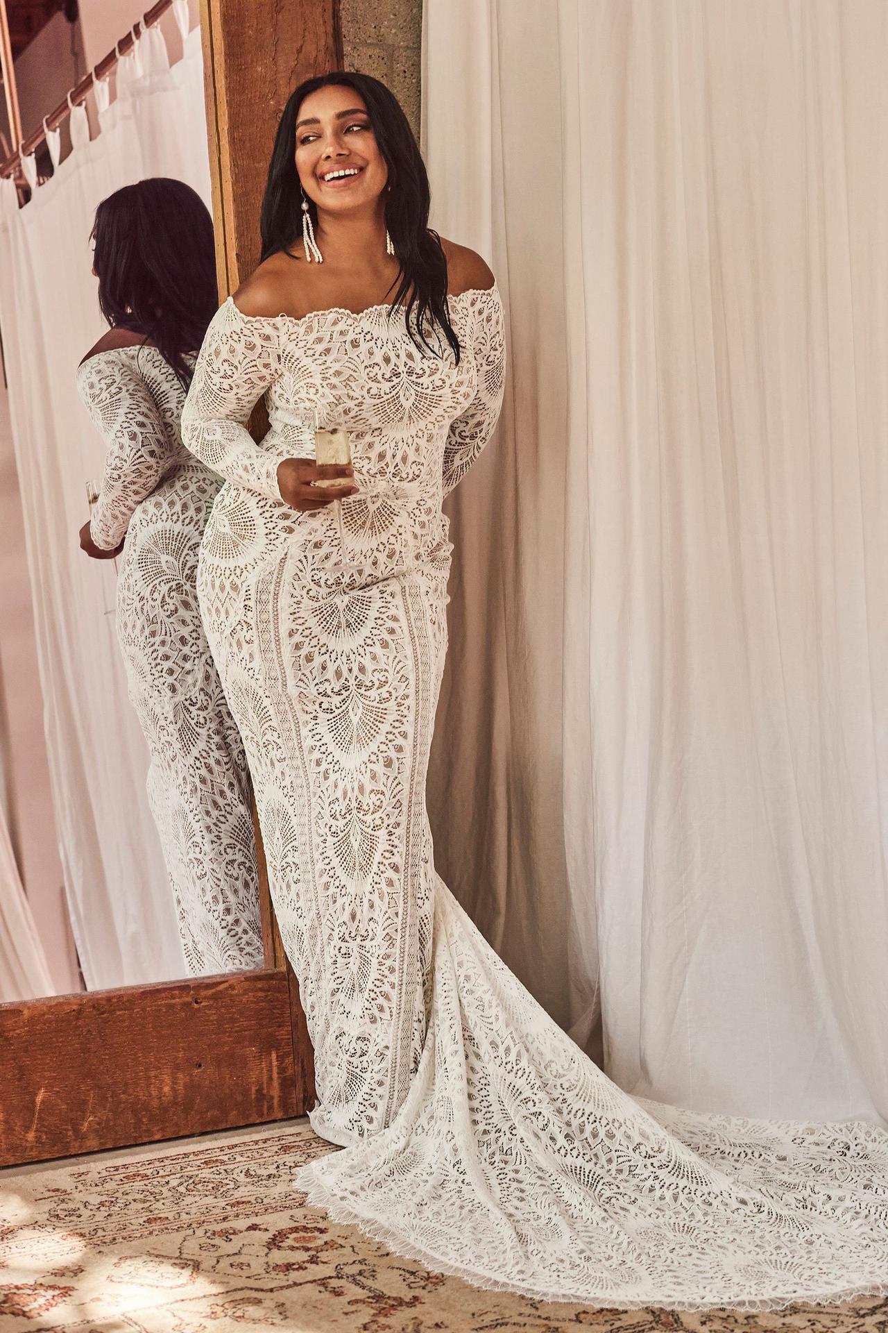 Model wearing an off the shoulder lace long sleeved wedding dress