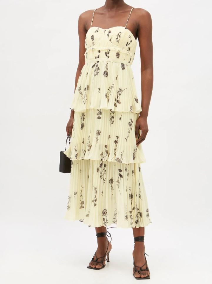 Model wearing pale yellow midi dress with thing spaghetti straps, sweetheart neckline and tiered skirts with floral pattern