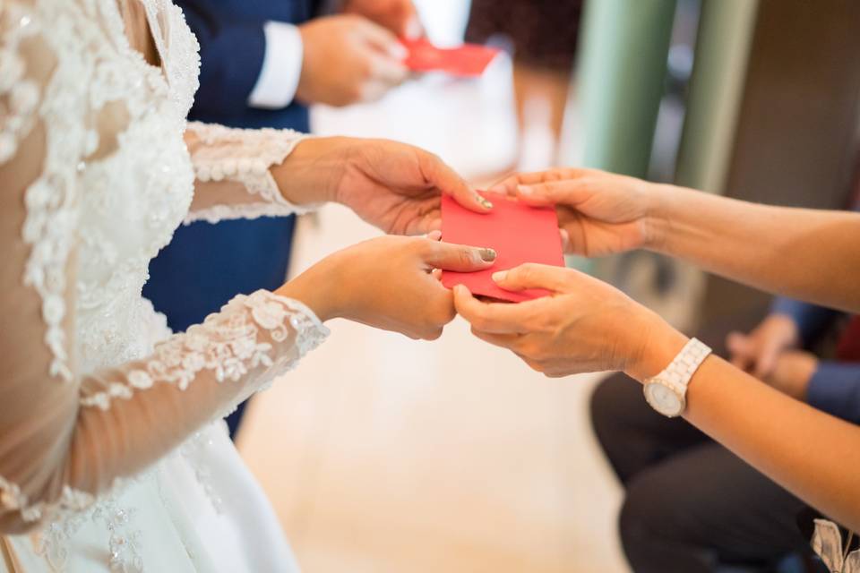 Couple being handed a money gift in a red envelope at a wedding