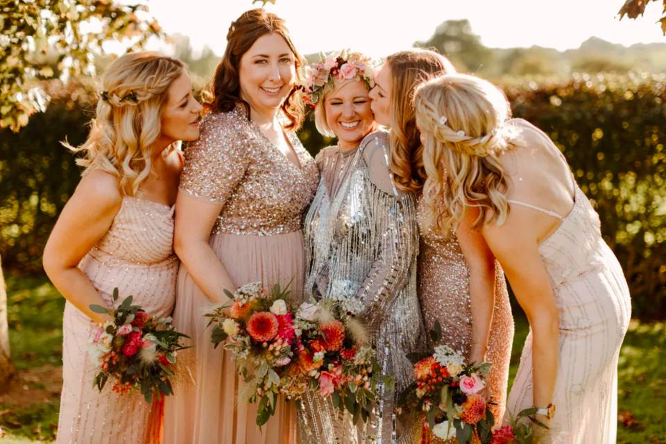 A bride in silver wearing a pink flower crown with four bridesmaids